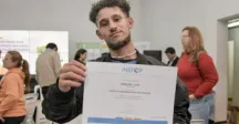 Uno de los egresados de los cursos de informática y autoelevadores mostrando su diploma a la cámara 