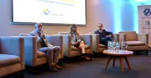 Tres personas sentadas en mesa de apertura de un evento 