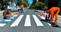 Personas pintando los pictogramas en un cruce peatonal 
