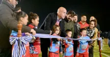 Niños y adultos cortando una cinta de inauguración